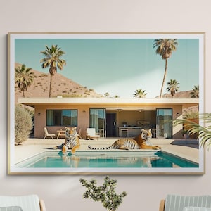 May include: A framed art print shows a mid-century modern home with a pool, palm trees, and two tigers. The print hangs above a round wooden table surrounded by six wooden chairs with striped blue cushions. The room has a hardwood floor.