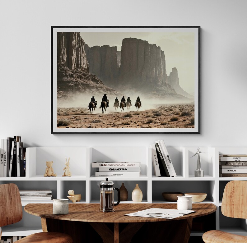 May include: A framed photograph of a group of people riding horses through a desert landscape. The horses are silhouetted against a hazy, dusty background. The landscape is dominated by tall, red rock formations.