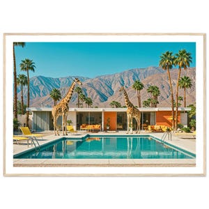 以下が含まれることがあります： 鮮やかな青い空と山々を背景に、ターコイズブルーのプール、ヤシの木、2頭のキリンが特徴のミッドセンチュリーモダンな家を描いた額入りのプリント。プリントは明るい木製のフレームに入っています。