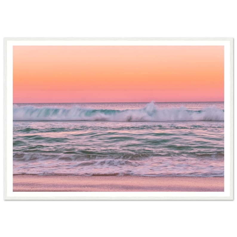 May include: A pink and orange sunset over a turquoise ocean with white foamy waves crashing on the shore. The sand is a light pink color.