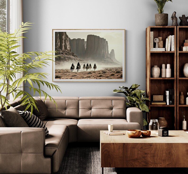 May include: A framed photograph of a group of people riding horses through a desert landscape. The photograph is in a light wood frame and is hanging on a wall in a living room.