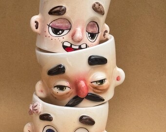 気まぐれな花の顔のマグカップ | 手作りの陶器のカップに彫刻された顔 