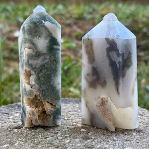 Könnte beinhalten: Zwei grüne, weiße und braune Agat-Kristalltürme. Die Türme sind poliert und haben eine glatte, glänzende Oberfläche. Die Kristalle sind etwa 10 cm hoch.