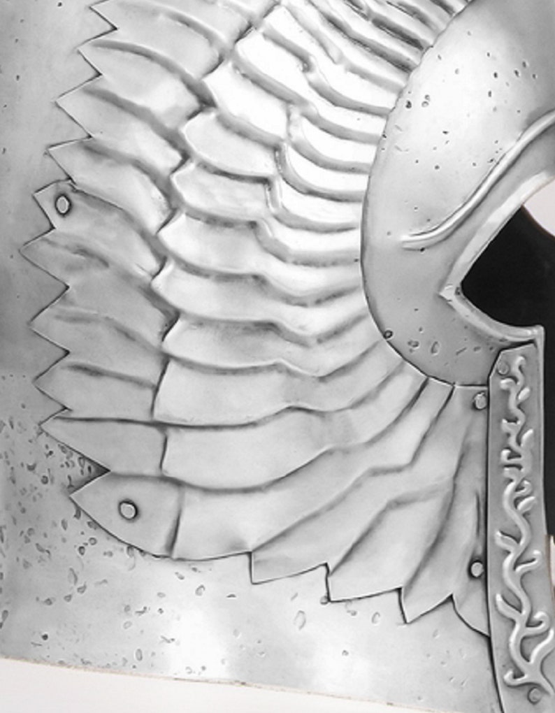 May include: A silver helmet with a winged design. The helmet has a textured surface and a pointed top.