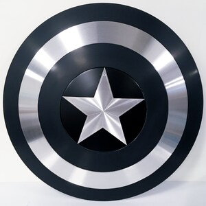 May include: A black and silver Captain America shield replica. The shield has a large, five-pointed star in the center.