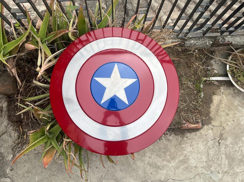 May include: A red, white, and blue Captain America shield with a five-pointed star in the center. The shield is made of metal and has a shiny finish.