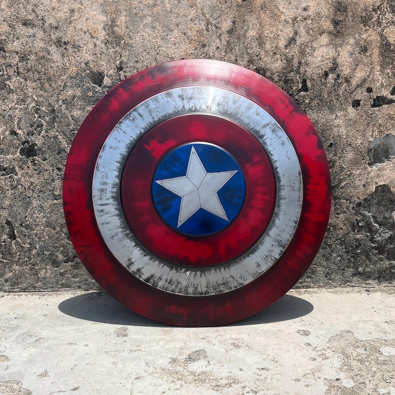 May include: A red, white, and blue Captain America shield with a distressed, weathered look. The shield has a large, white star in the center.