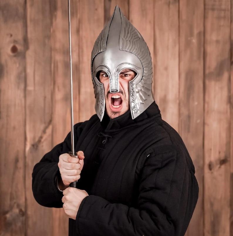 May include: A person wearing a silver helmet with a black quilted jacket and holding a sword. The helmet has a pointed top and a face mask with a fierce expression.