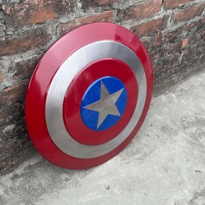 May include: A red, white, and blue Captain America shield with a silver star in the center. The shield is made of metal and has a glossy finish.