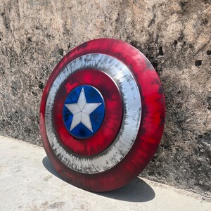 May include: A red, white, and blue Captain America shield with a silver star in the center. The shield has a distressed, weathered look.