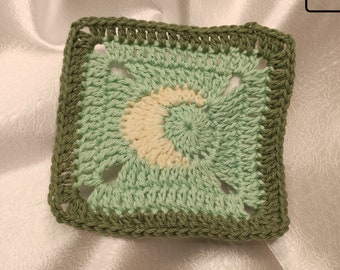 May include: A green crochet square with a white crescent moon design. The square has a dark green border. The text "Ropeful Crafts" is visible in the bottom center of the image.