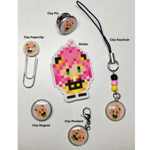 May include: A collection of handmade clay accessories featuring a pixelated character design. Items include a pin, paperclip, sticker, keychain, magnet, and pendant. The accessories are in various shapes and sizes, with a white background.