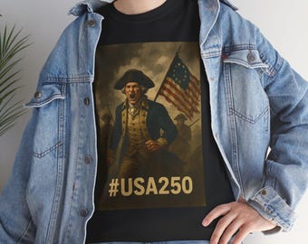 May include: Black t-shirt with a historical illustration of a man in a tricorn hat holding a flag with stars and stripes. The image includes the text #USA250 in gold. The shirt is worn with a blue denim jacket and jeans.