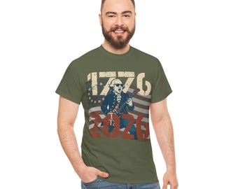 May include: Olive green t-shirt with a graphic of George Washington playing a guitar against an American flag backdrop. The numbers "1776" and "2020" are printed above and below the image.