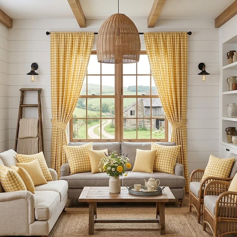 May include: A cozy living room with yellow gingham curtains and throw pillows. A woven pendant light hangs above a gray sofa and wooden coffee table. The room features a neutral color palette with a view of a rural landscape.