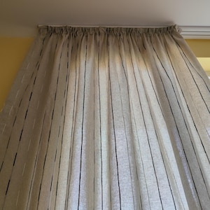 Peut inclure: Rideaux en lin beige avec de fines rayures noires. Les rideaux sont rassemblés en haut et tombent droit.