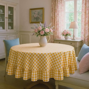 Può includere: Un tavolo rotondo coperto da una tovaglia a quadretti gialla e bianca. Una brocca bianca con rose rosa e lavanda è al centro. Il tavolo è in una sala da pranzo con una finestra e tende floreali.