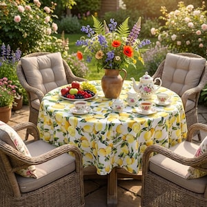 Può includere: Un tavolo rotondo da giardino per il tè, con una tovaglia stampata a limoni, circondato da sedie in vimini con cuscini beige. Un vaso di fiori colorati è al centro, con un piatto di frutta e un servizio da tè.