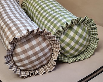 May include: Two cylindrical bolster pillows featuring a gingham check pattern. One pillow is in shades of beige and white, while the other is in shades of green and white. Both pillows are finished with a gathered, ruffled fabric trim at the ends.