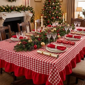 May include: A rectangular tablecloth featuring a red and white gingham check pattern with a solid red ruffled border. The tablecloth is draped over a dining table set with clear glassware, white plates, and red cloth napkins with gold rings.