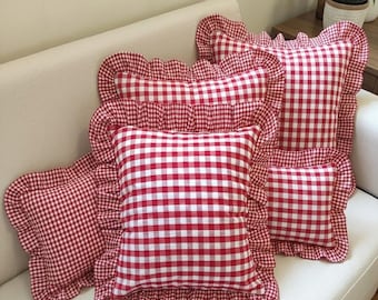 May include: A collection of square throw pillows featuring a red and white gingham check pattern. Each pillow is finished with a ruffled border made from the same checkered fabric. The pillows are arranged in a cluster, displaying the consistent pattern.