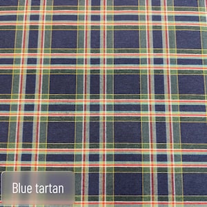 Pode incluir: Um tecido com um padr&atilde;o de xadrez azul com linhas horizontais e verticais que se cruzam em tons de verde, vermelho, amarelo e branco. O t&ecirc;xtil apresenta um design de grade repetitivo com o texto Blue tartan vis&iacute;vel no canto.