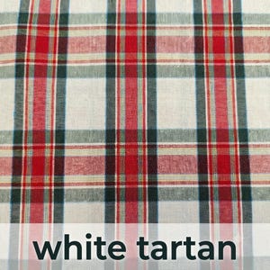 Pode incluir: Um tecido com uma base branca e um padr&atilde;o xadrez repetitivo composto por riscas verticais e horizontais em tons de vermelho, verde escuro e linhas amarelas finas. O texto "white tartan" est&aacute; impresso a preto na parte inferior.
