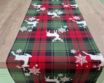 Pode incluir: Um corredor de mesa xadrez verde e vermelho com um design de floco de neve e rena branca.
