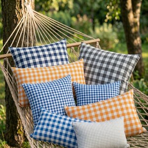 May include: A hammock filled with various gingham-patterned pillows in shades of blue, orange, gray, and white. The pillows are rectangular and square, creating a cozy and inviting outdoor scene.