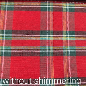 Pode incluir: Um tecido com um padr&atilde;o cl&aacute;ssico de xadrez tartan em vermelho, verde escuro e preto. O design inclui linhas finas que se cruzam em branco e amarelo, criando uma grade estruturada. A superf&iacute;cie tem uma textura mate sem brilhos.