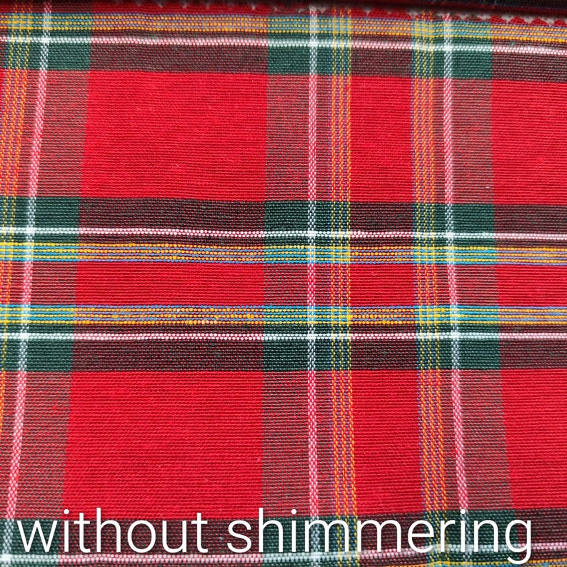 Pode incluir: Um tecido com um padr&atilde;o cl&aacute;ssico de xadrez tartan em vermelho, verde escuro e preto. O design inclui linhas finas que se cruzam em branco e amarelo, criando uma grade estruturada. A superf&iacute;cie tem uma textura mate sem brilhos.
