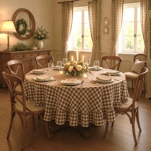 May include: A dining room set with a round table covered in a brown and white checkered tablecloth. The table is set with plates, glasses, and a floral centerpiece. Wooden chairs surround the table, and the room has a warm, inviting atmosphere.