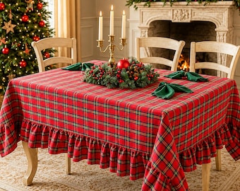 Pode incluir: Uma toalha de mesa retangular com padrão xadrez vermelho, verde e amarelo e uma borda com babados. A toalha está estendida sobre uma mesa e apresenta três guardanapos de tecido verde-escuro dobrados, além de um candelabro de latão com três velas.