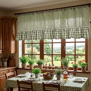 May include: A sage green and white gingham window valance featuring a ruffled bottom edge with a delicate white scalloped trim. The curtain is hung on a dark wooden rod and covers the top portion of a window, displaying a classic checkered pattern.