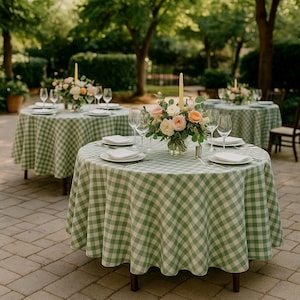 Può includere: Tavoli da pranzo all'aperto allestiti per un evento. Ogni tavolo è coperto da una tovaglia a quadri verdi e bianchi e apparecchiato con piatti bianchi, posate e calici. Centrotavola floreali e candele completano l'atmosfera.