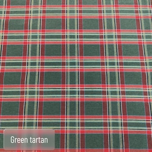 Pode incluir: Um tecido com um padr&atilde;o de tartan verde com linhas horizontais e verticais que se cruzam em vermelho, branco e preto. O t&ecirc;xtil apresenta um design xadrez repetitivo em toda a superf&iacute;cie, com o texto Green tartan vis&iacute;vel.