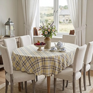 May include: An oval dining table covered with a yellow and grey plaid tablecloth, surrounded by six upholstered chairs. On the table sits a ceramic vase with flowers, a fruit bowl with berries and a pear, a teapot, and two matching teacups.