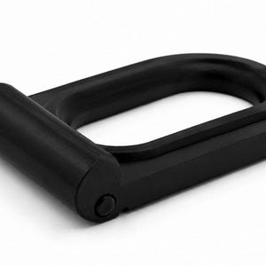 Könnte beinhalten: Ein mattschwarzes D-Ring-Beschlagteil mit einer klappbaren, zylindrischen Basis und einer abgerundeten, rechteckigen Schlaufe. Das Objekt hat eine glatte, solide Oberfläche und einen mechanischen Drehpunkt an der Seite zur Befestigung.
