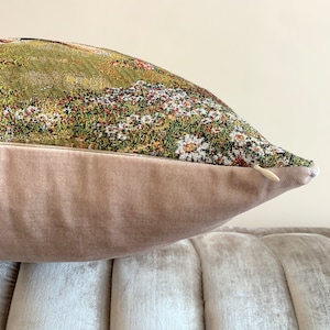 May include: A decorative throw pillow with a floral tapestry design and a light brown velvet back.