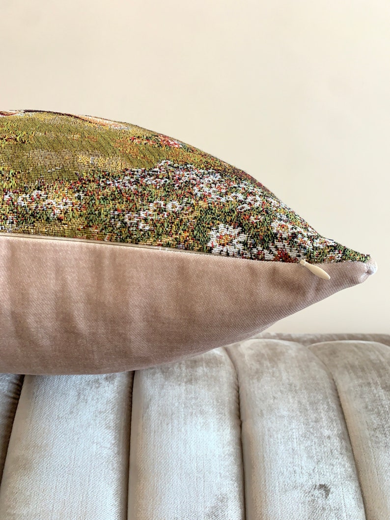 May include: A decorative throw pillow with a floral tapestry design and a light brown velvet back.