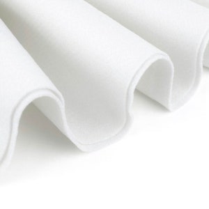Peut inclure: Gros plan sur un tissu blanc plié en forme de vague. Le tissu est lisse et doux, avec un léger brillant.