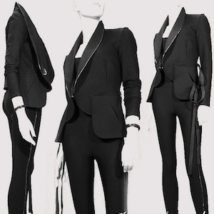 May include: Three mannequins display a black blazer with a contrasting lapel and a single pocket. The blazer is paired with matching black leggings. The outfits are accessorized with a black bracelet and a black ribbon detail.