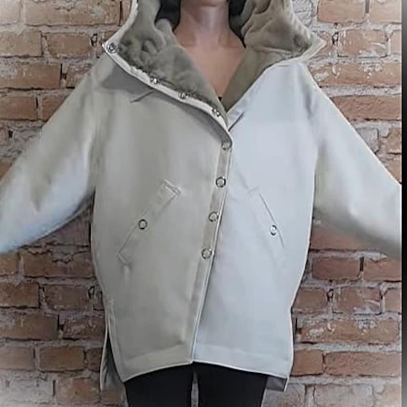 May include: A light-colored jacket with a faux fur-lined hood. The jacket has a button-up front, two pockets, and a relaxed fit. The jacket is a neutral color, suitable for various outfits.