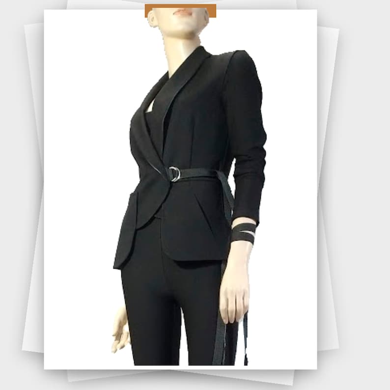 May include: Black blazer with a notched lapel, a matching belt with a silver buckle, and long sleeves. The blazer is paired with black pants. The outfit is displayed on a mannequin.