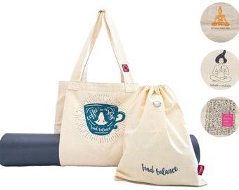 Puede incluir: Una bolsa de mano beige con un diseño de taza de café azul y postura de yoga que dice "coffee and yoga find balance". Una bolsa de cordón beige con el texto "find balance" está al lado de la bolsa de mano. Una esterilla de yoga gris está delante de las bolsas. Tres parches redondos de tela beige con diferentes diseños de temática de yoga están en el fondo.