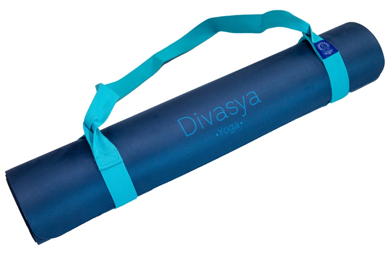 Puede incluir: Una esterilla de yoga azul con una correa de transporte turquesa. La esterilla tiene el texto "Divasya Yoga" impreso en ella.