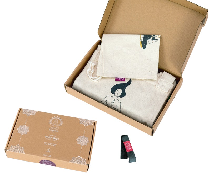 Puede incluir: Una caja de cart&oacute;n marr&oacute;n con una bolsa de yoga blanca en su interior. La bolsa tiene una ilustraci&oacute;n en blanco y negro de una mujer meditando. La caja est&aacute; etiquetada con "Yoga Bag".