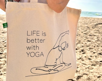 May include: A white canvas tote bag with a black line drawing of a person doing yoga. The text "LIFE is better with YOGA" is printed on the bag.
