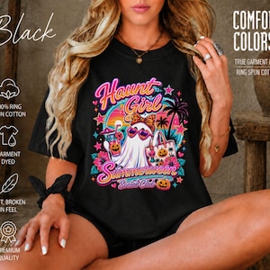 Puede incluir: Una camiseta negra con un estampado gr&aacute;fico de un fantasma con gafas de sol en forma de coraz&oacute;n y un lazo de leopardo. El texto dice Haunt Girl Summerween Social Club. El dise&ntilde;o incluye palmeras, flores de hibisco y calabazas.