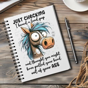May include: A white spiral bound notebook with a cartoon horse on the cover. The horse has blue and brown fur and is looking to the right. The text on the cover reads "JUST CHECKING I heard a loud pop and thought you might have pulled your head out of your ASS".